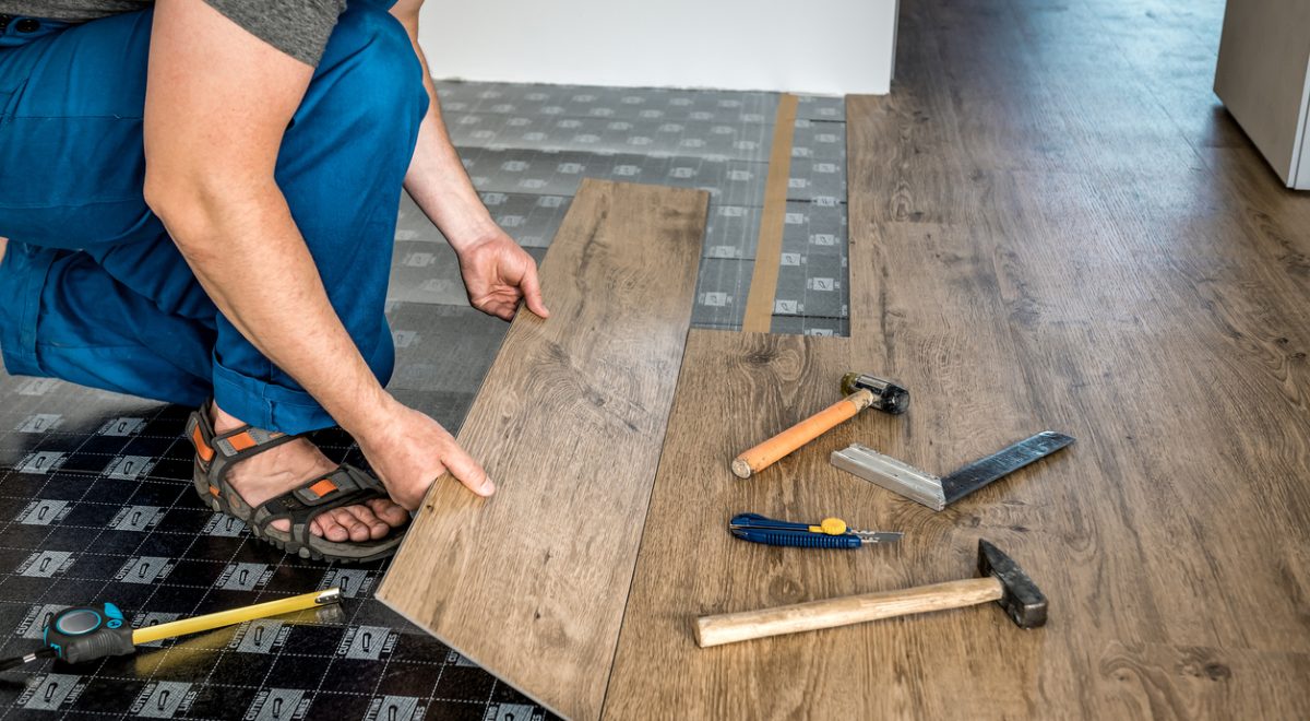 vīrietis ieklāj vinila grīdas segumu